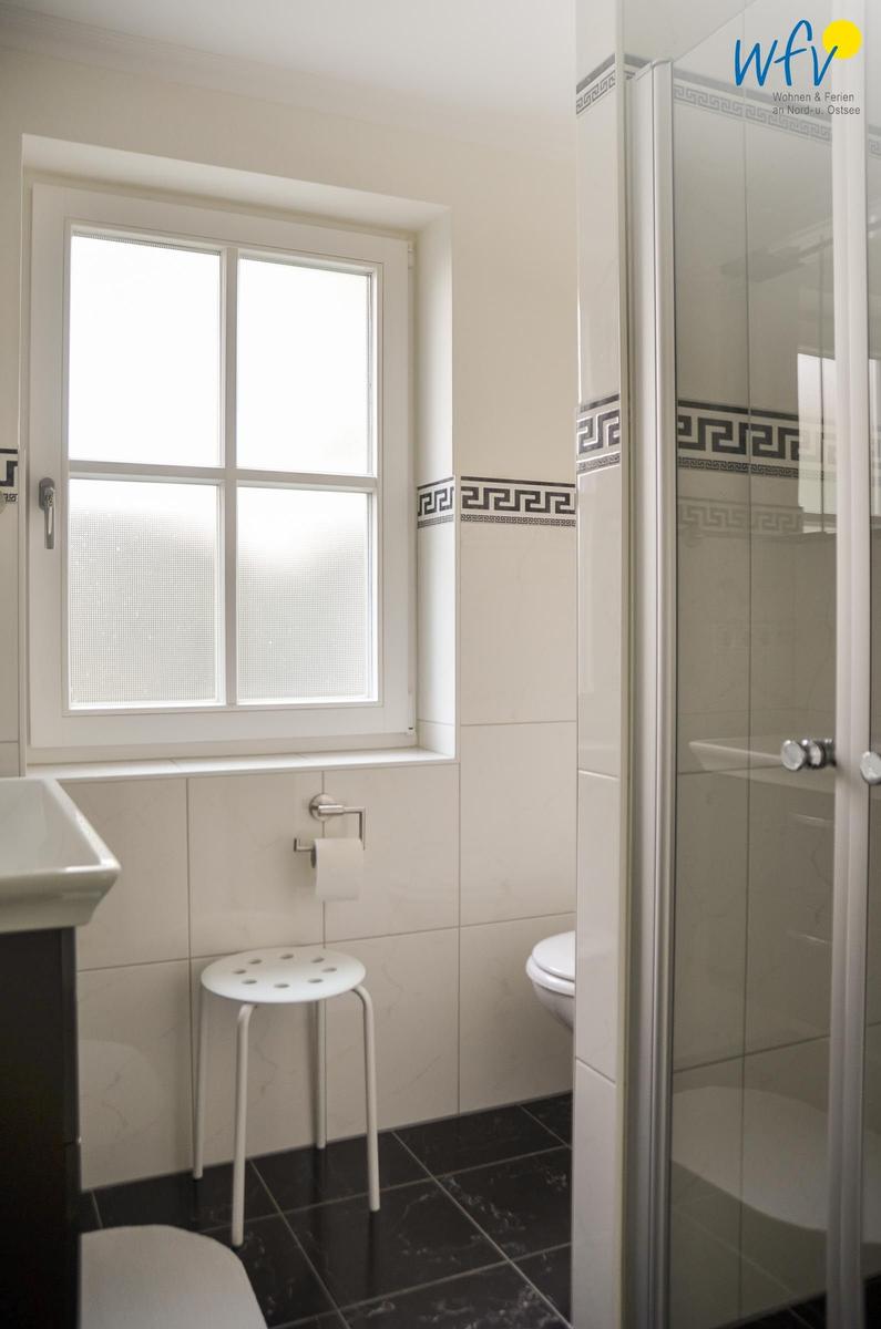 Badezimmer mit Dusche, Toilette und Fenster mit Milchglas