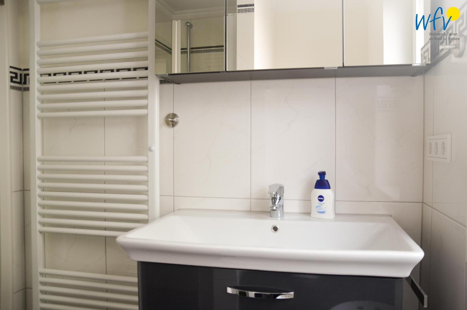 Badezimmer mit Waschbecken, Spiegelschrank und Heizkörper