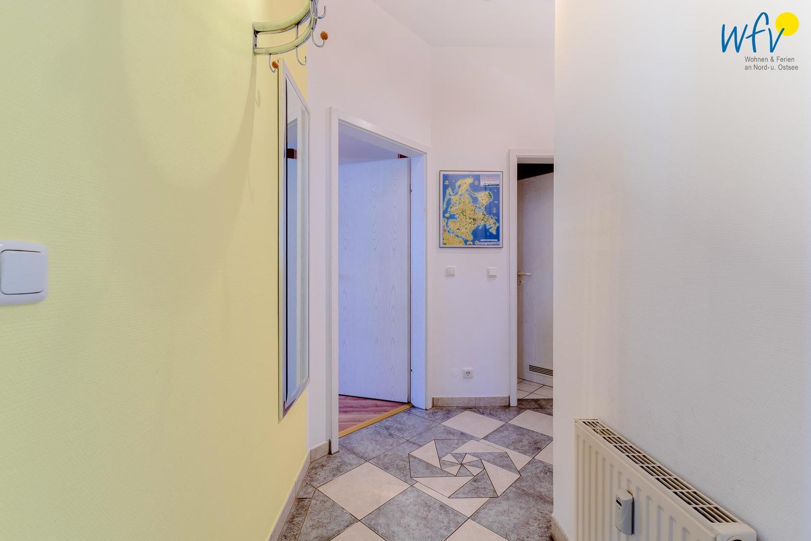 Flur mit gemustertem Boden, gelber Wand und Karte an der Wand.