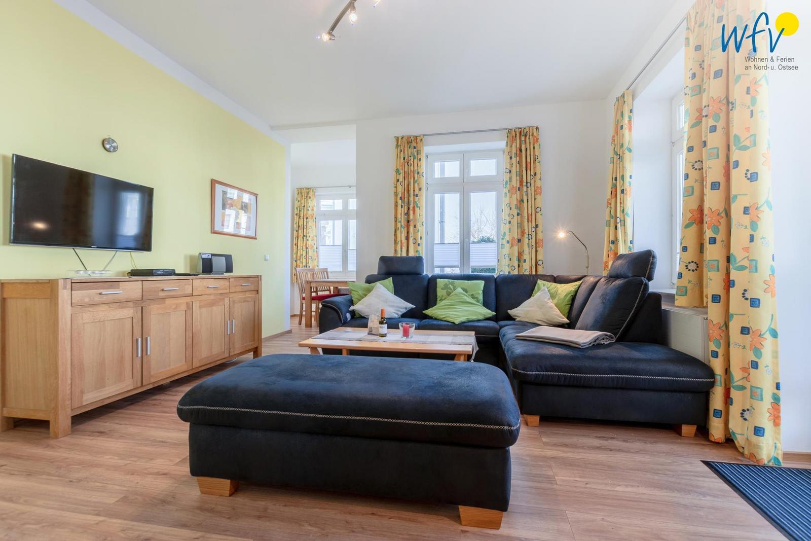 Wohnzimmer mit Sofa, Couchtisch und Fernseher an der Wand.