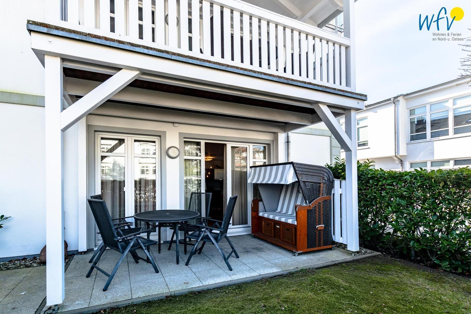 Terrasse mit Tisch, Stühlen und Strandkorb unter Dach
