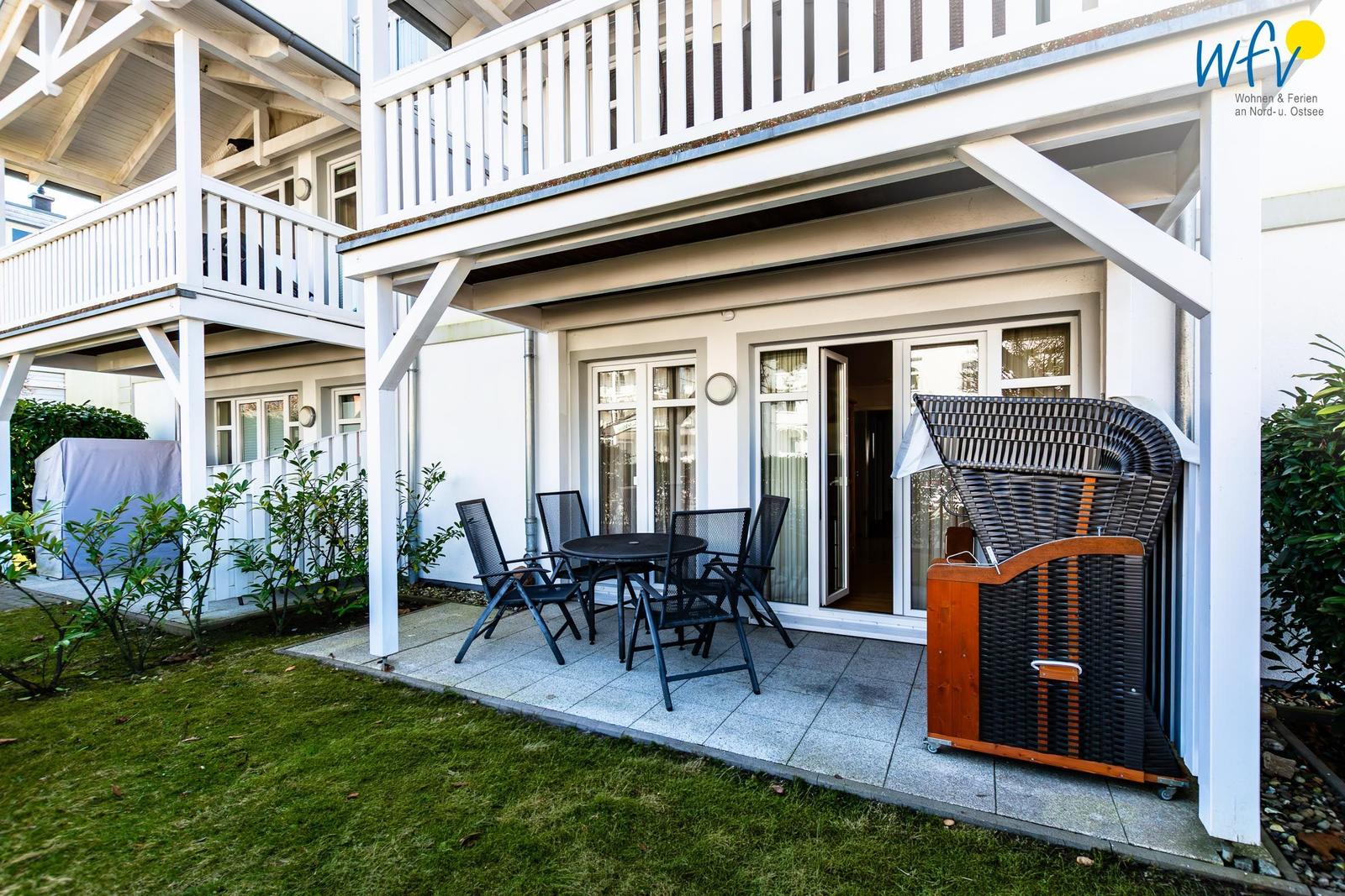 Terrasse mit Tisch und Stühlen, angrenzender Eingang und Gartenbereich.