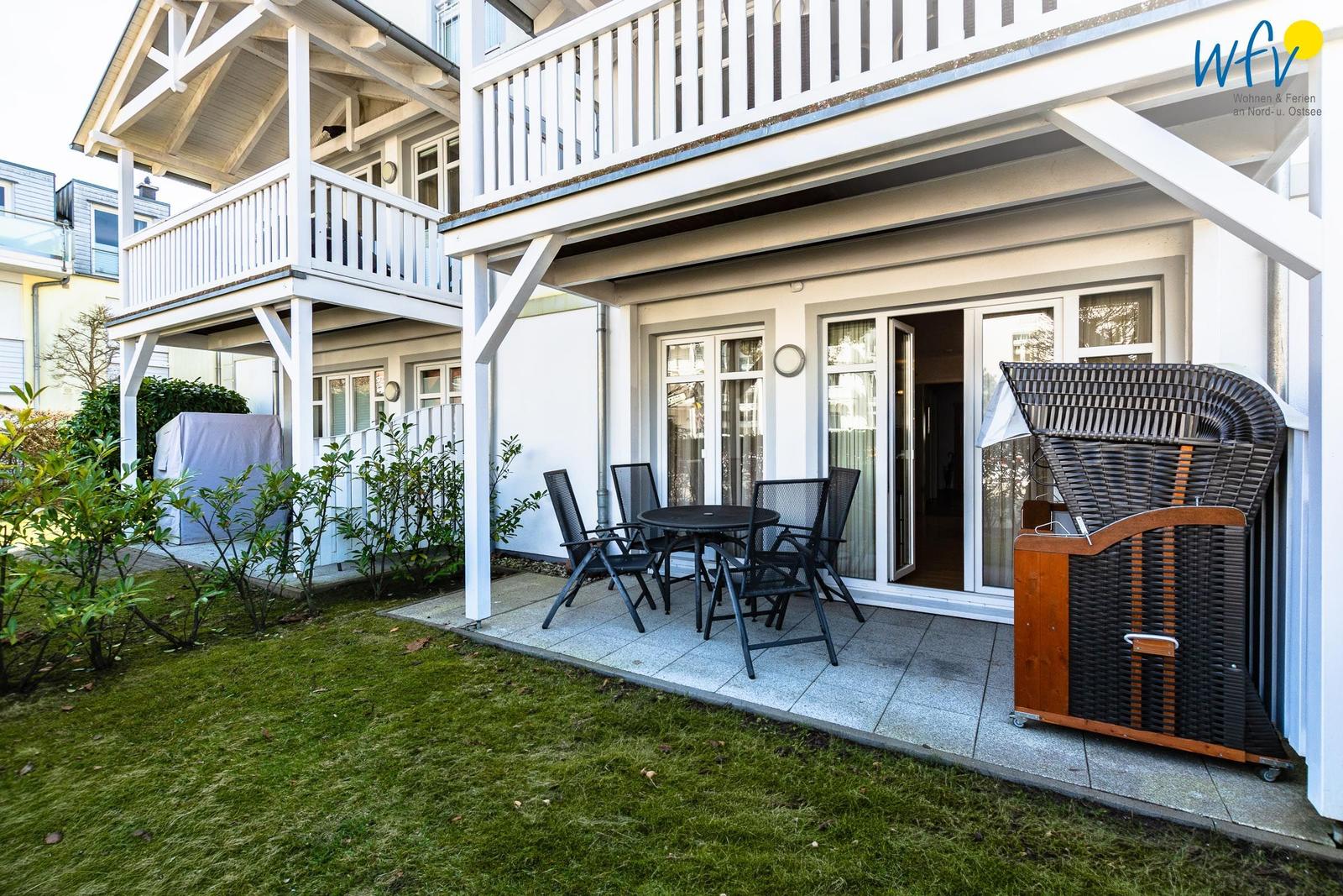 Terrasse mit Tisch und Stühlen, Gartenbereich und Balkon an der Fassade.