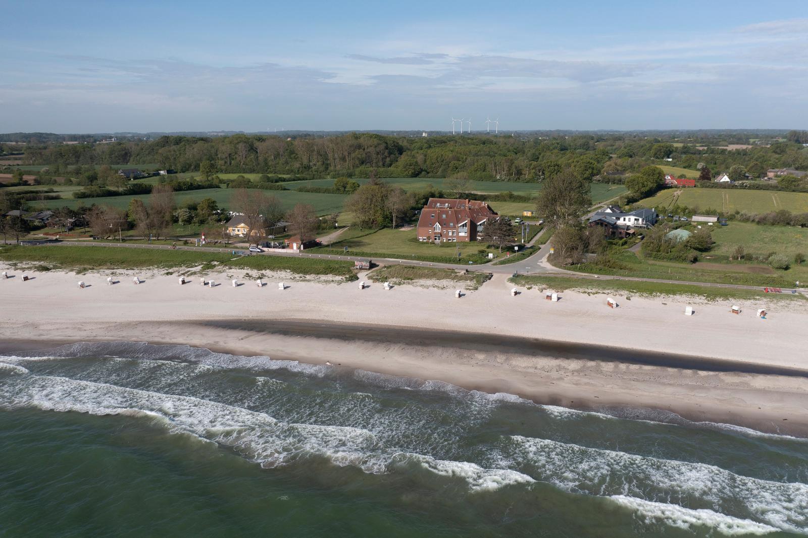 Strand mit Wellen, Strandkörben und Häusern im Hintergrund