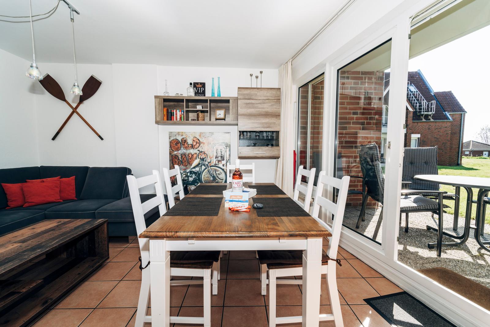 Essbereich mit Tisch und Stühlen, Sofa mit Kissen, Terrasse und Glaswand.