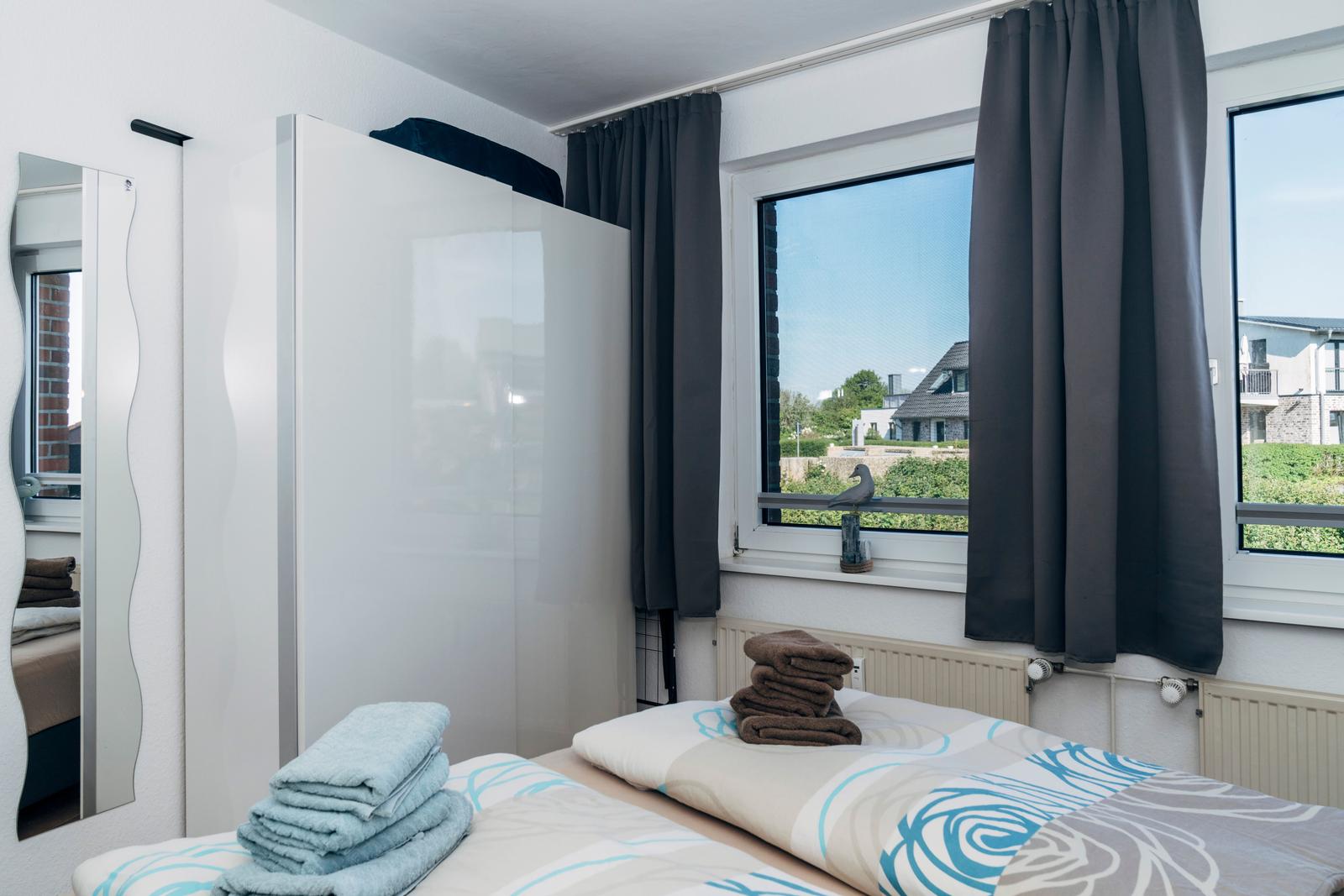 Schlafzimmer mit Bett, Gardinen und Blick auf Außenbereich.