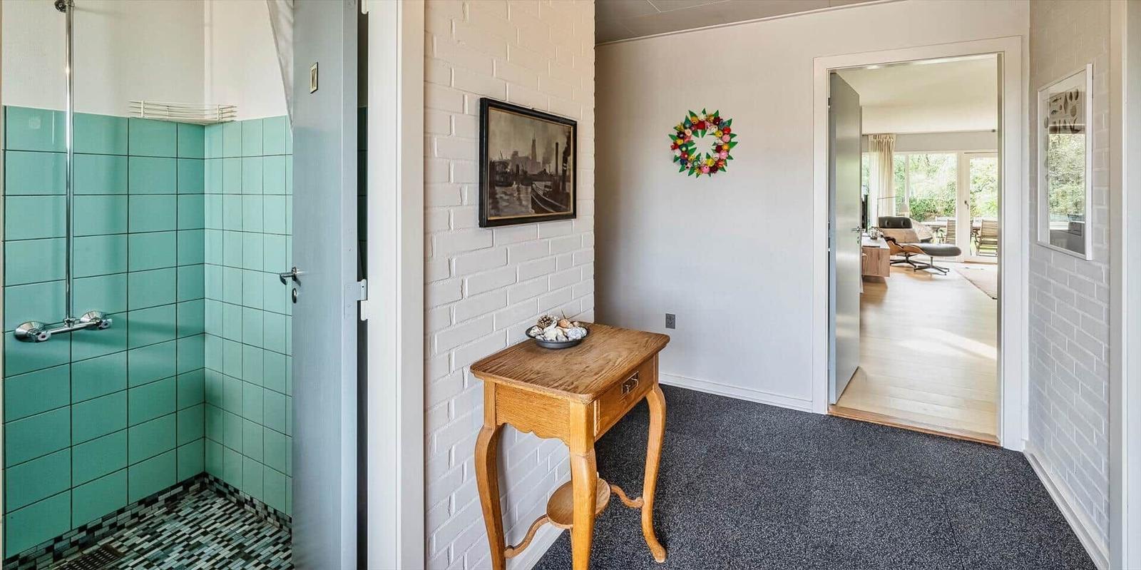 Flur mit Holztablett, Bild an Wand und Blick in Wohnbereich mit Sitzgelegenheit.