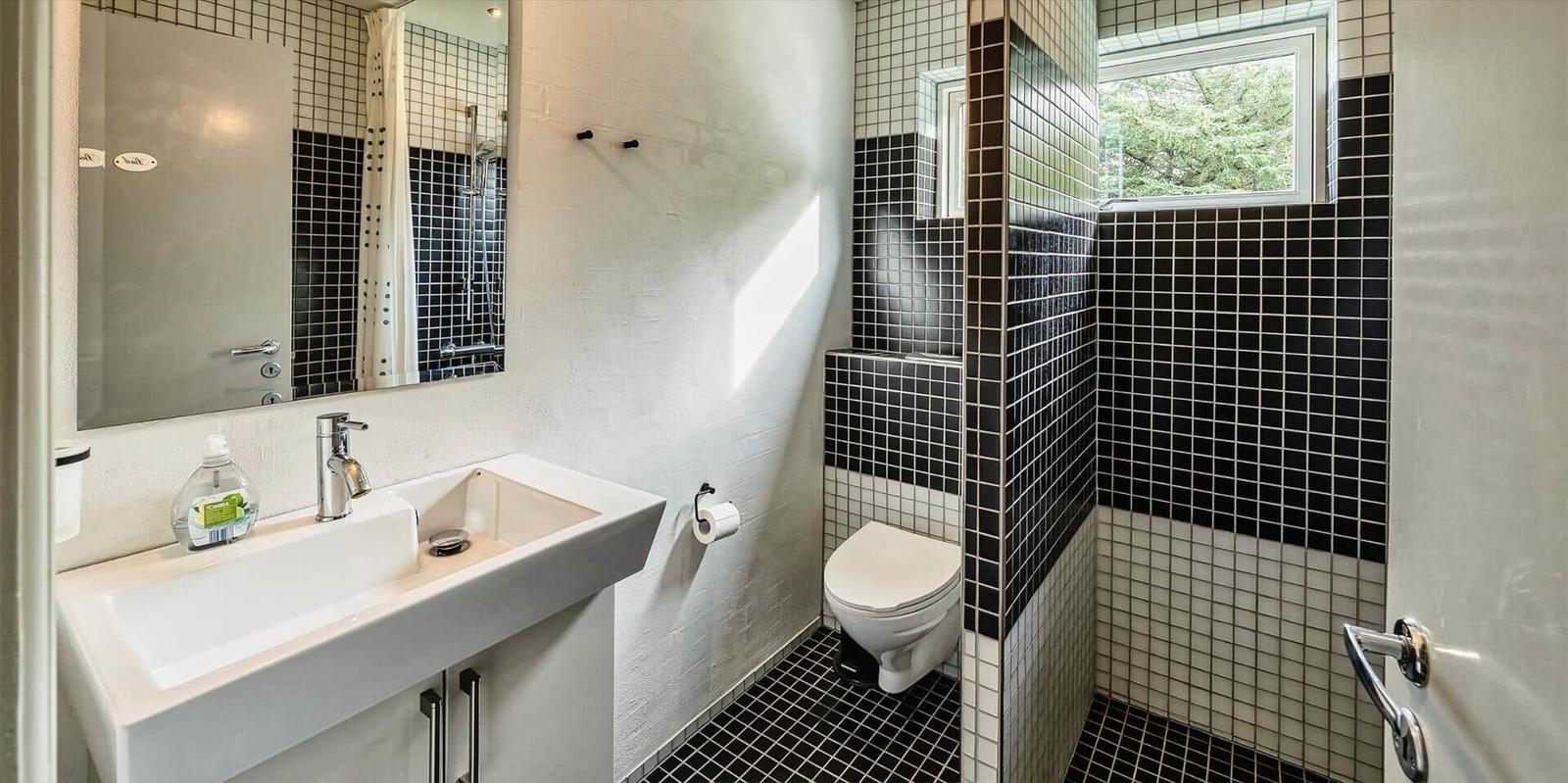 Badezimmer mit Dusche, Toilette und Waschbecken mit Spiegel.