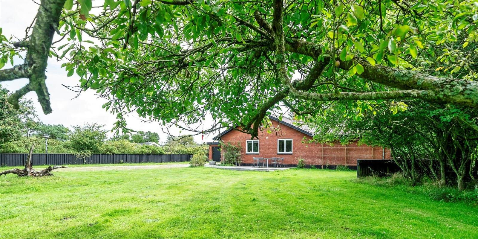 Rotes Haus mit Garten und Tisch unter Bäumen