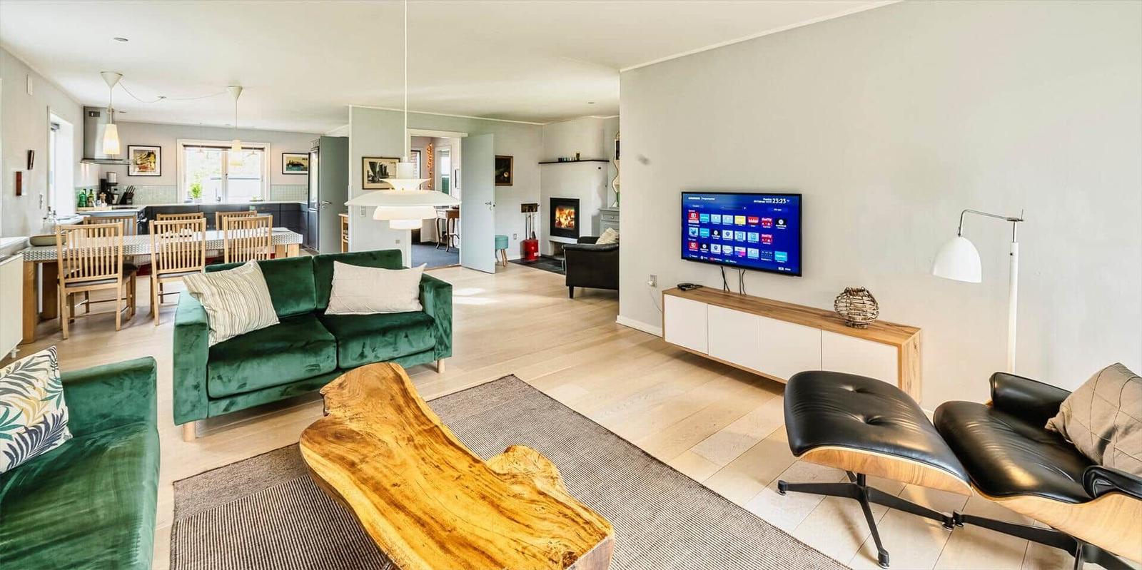 Wohnzimmer mit grünem Sofa, Holztisch und Fernseher an der Wand.