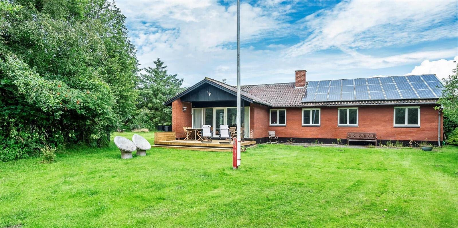 Rotes Haus mit Solaranlage und Terrasse im Garten.