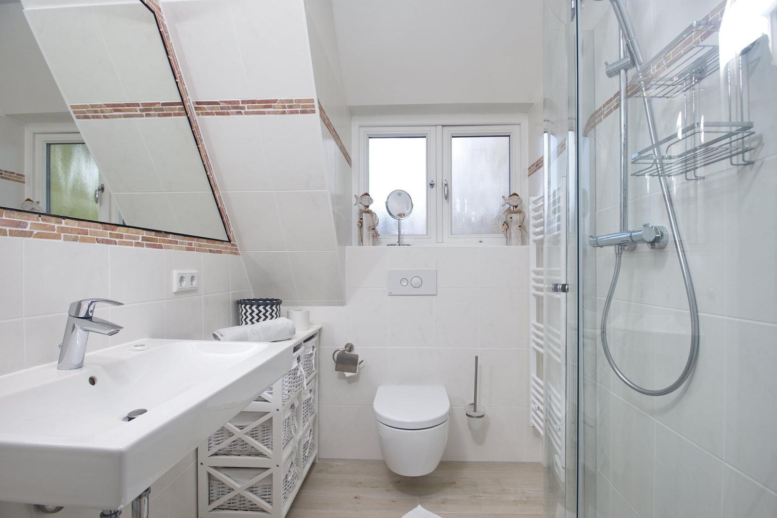 Badezimmer mit Dusche, Waschbecken und Toilette unter Dachschrägen.