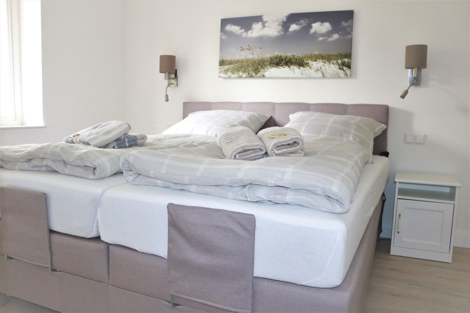 Doppelbett mit Bettwäsche, Wandbild und Nachttisch