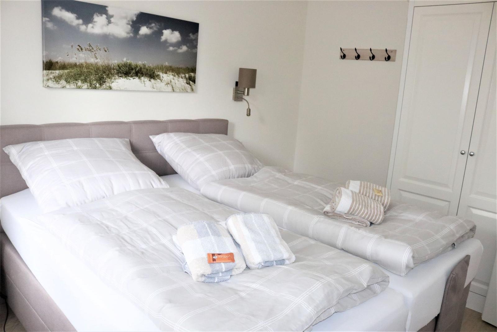 Schlafzimmer mit Doppelbett, Wandbild und Kleiderhaken.
