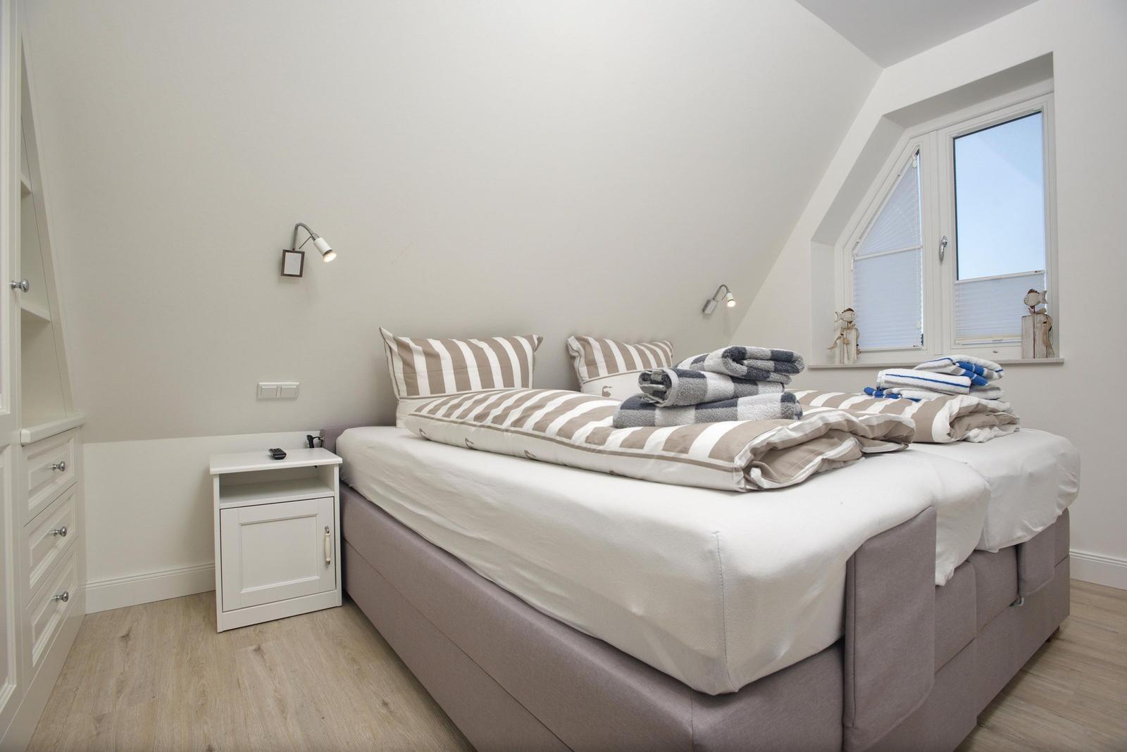 Schlafzimmer mit Doppelbett, Nachttisch und Fenster