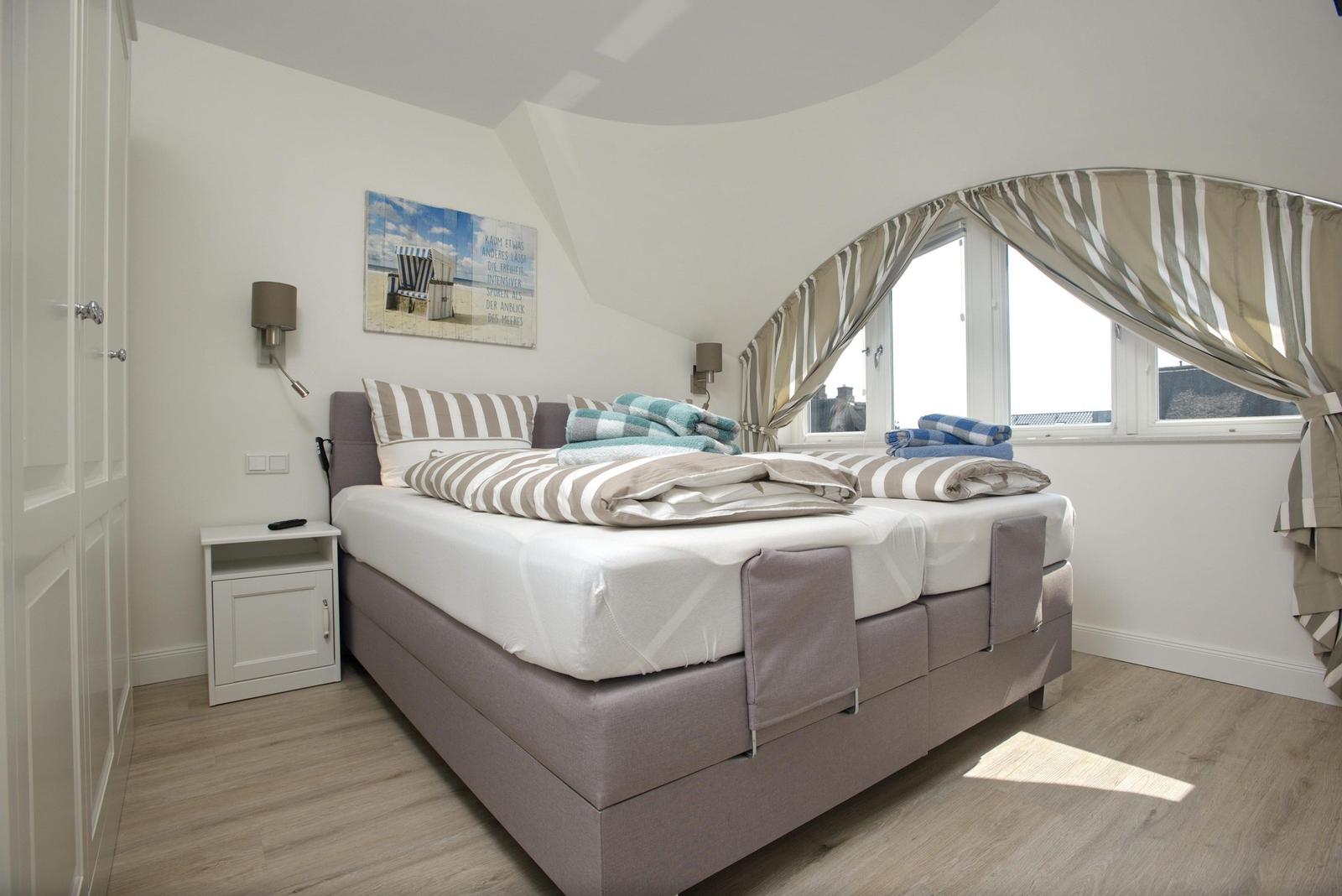 Schlafzimmer mit Doppelbett, Fenster und Wandbild.