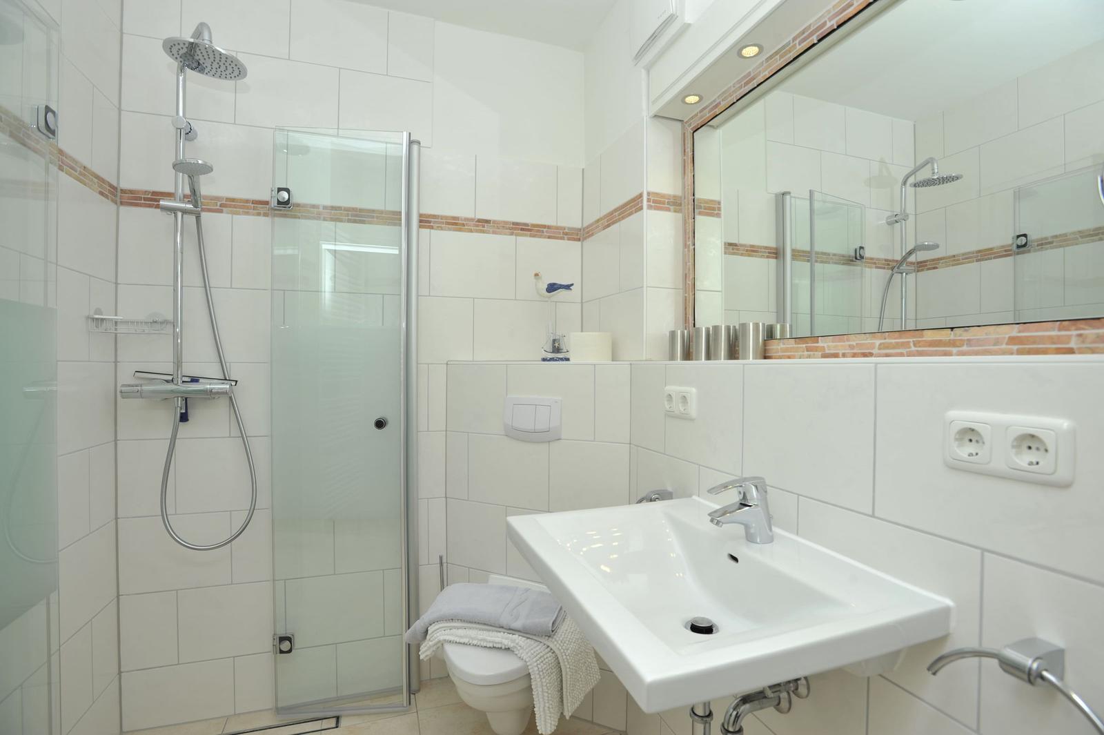 Badezimmer mit Dusche, Waschbecken und Spiegel