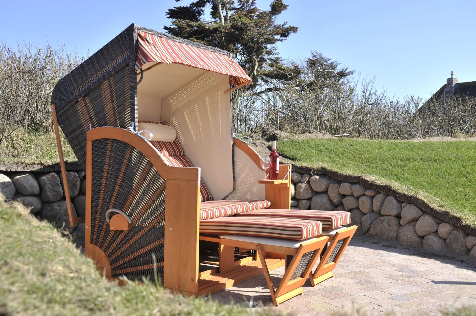 Strandkorb mit Sitzbank und Weinflasche auf Steinmauer