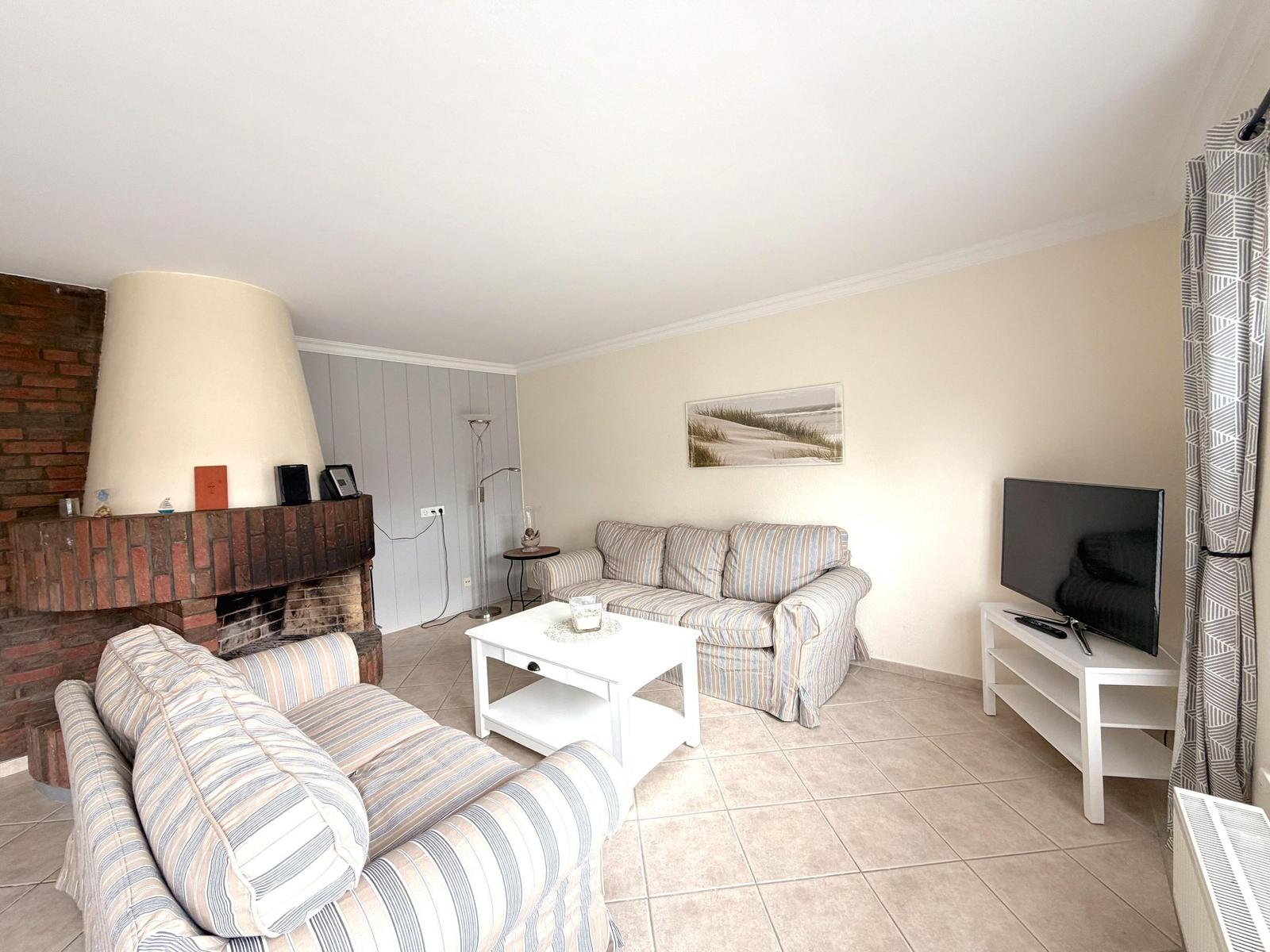 Wohnzimmer mit Sofa, Kamin und Fernseher.
