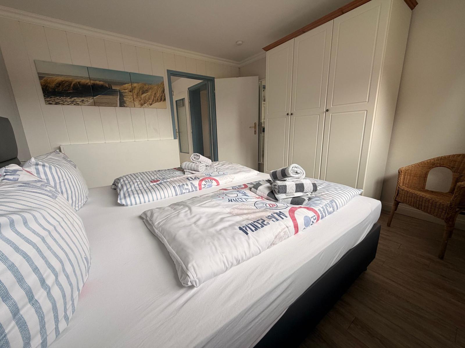 Schlafzimmer mit Bett, Kleiderschrank und Stuhl.