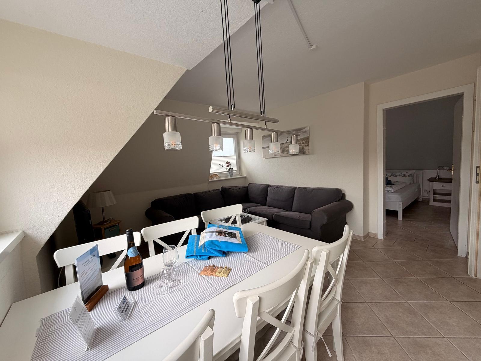 Essbereich mit Tisch und Stühlen, Wohnzimmer mit Sofa und Schlafzimmer im Hintergrund.