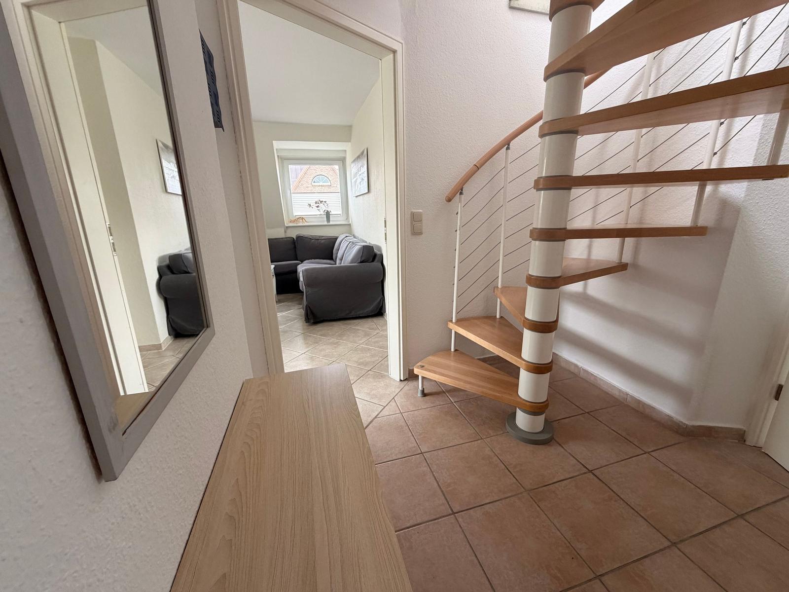 Haus mit Treppe und Spiegel. Wohnzimmer mit Sofa und Fenster.