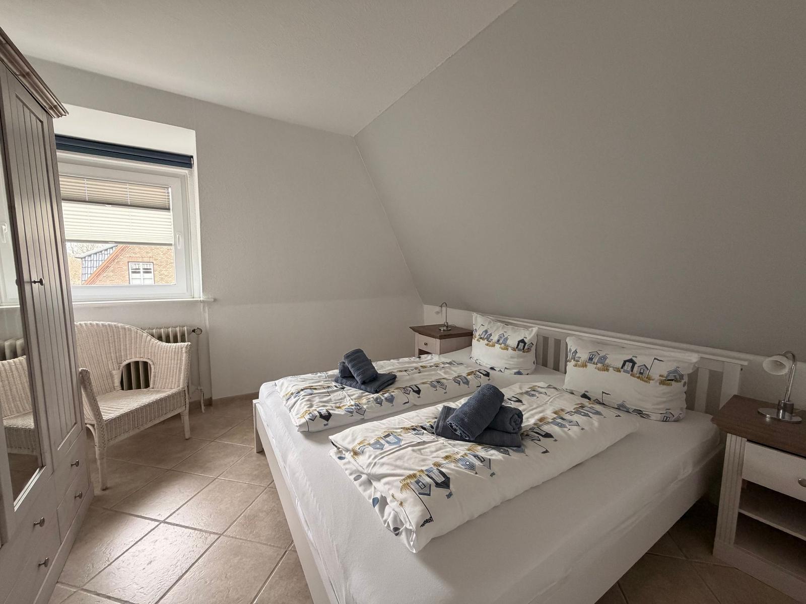 Schlafzimmer mit Doppelbett, Nachttischen und Fenster.