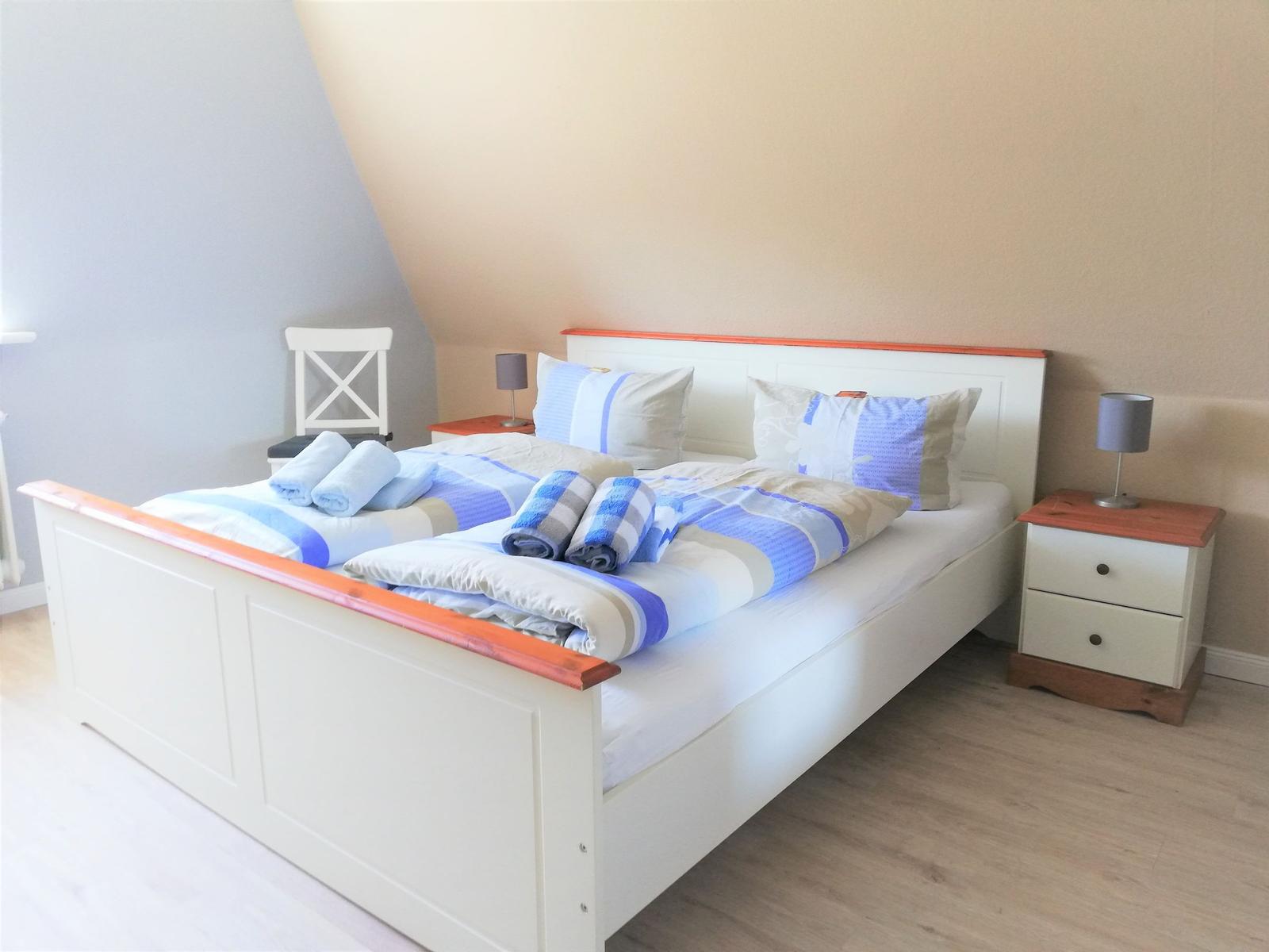 Schlafzimmer mit Doppelbett, Nachttischen und Bettwäsche.