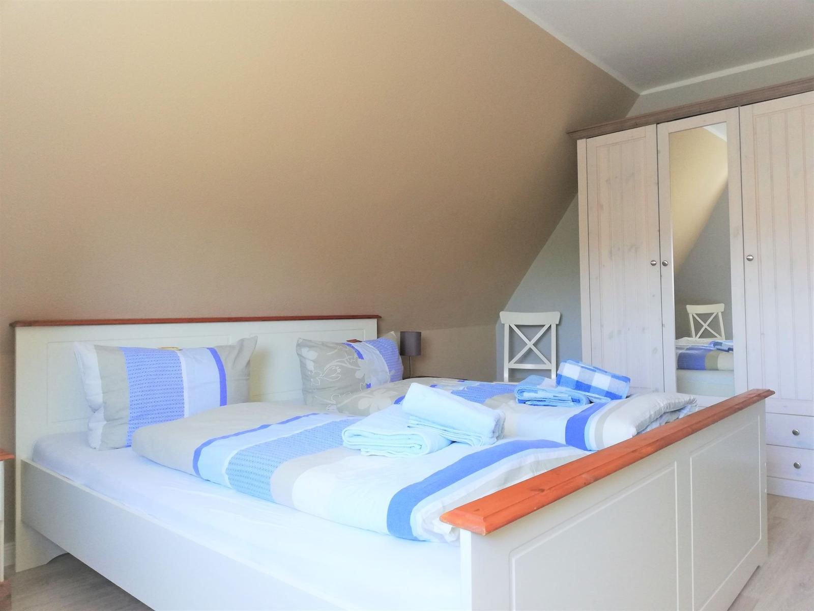 Schlafzimmer mit Bett, Kleiderschrank und Stuhl