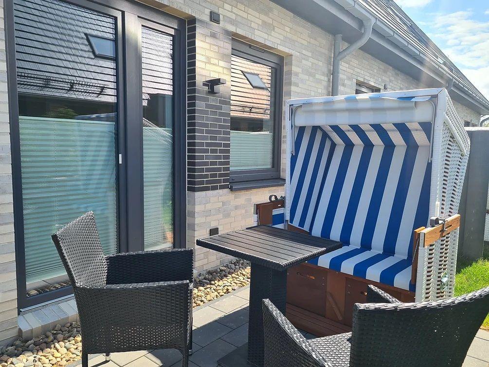 Terrasse mit Liegestuhl, Tisch und Stühlen vor Hauswand.