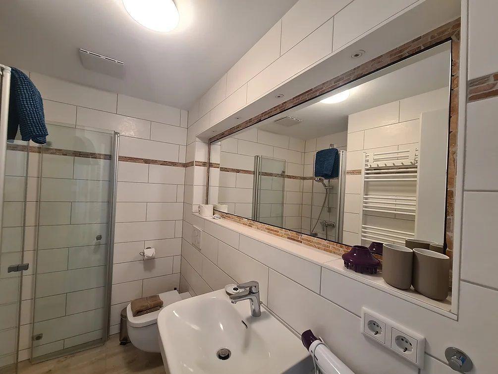 Badezimmer mit Dusche, Waschbecken und Spiegel