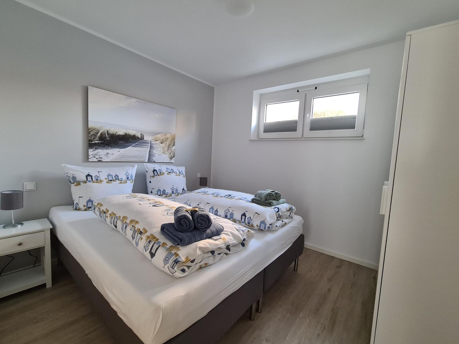 Schlafzimmer mit Doppelbett, Fenster und Kleiderschrank.