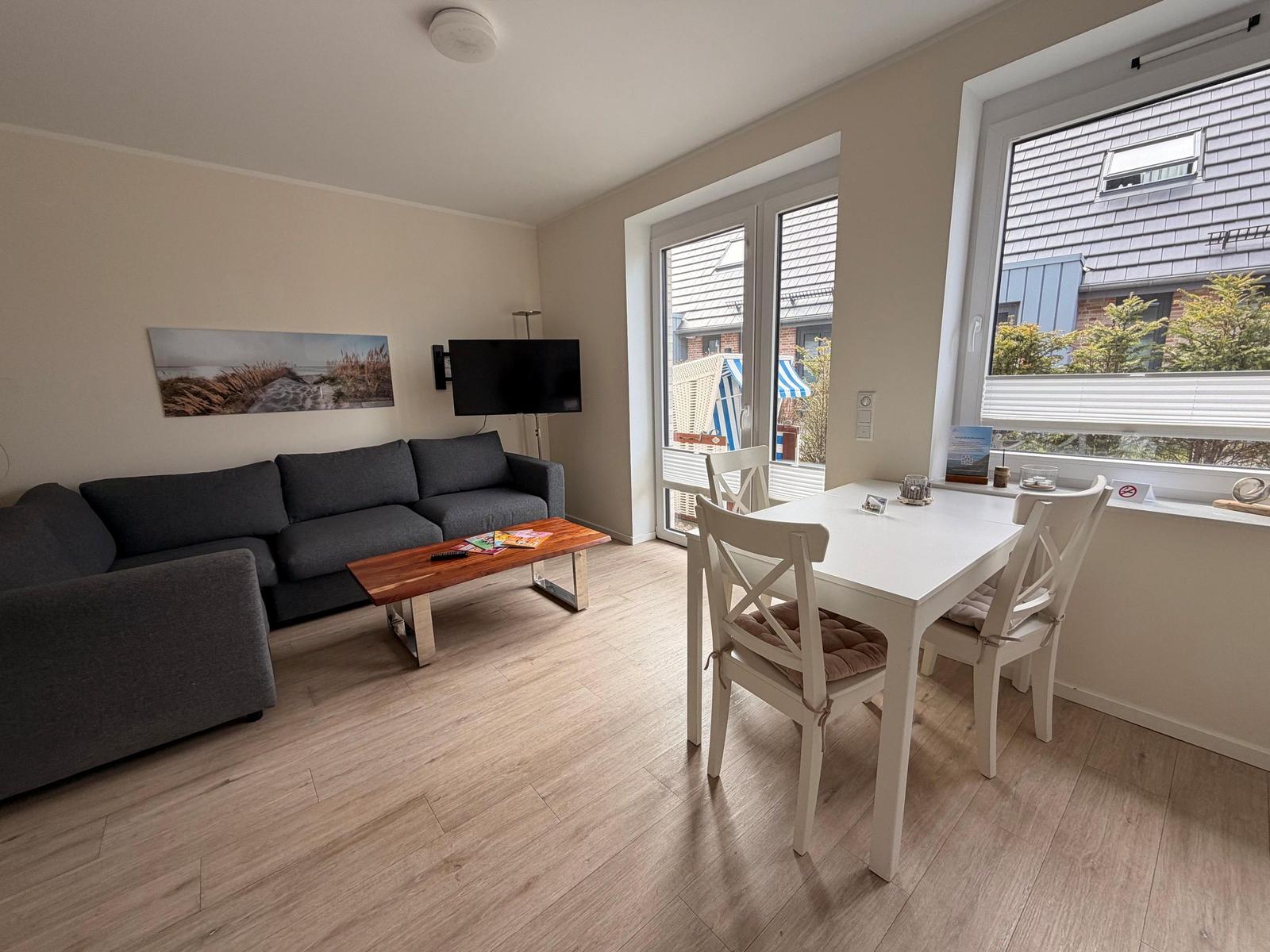 Wohn- und Essbereich mit Sofa, TV und Tisch mit Stühlen.