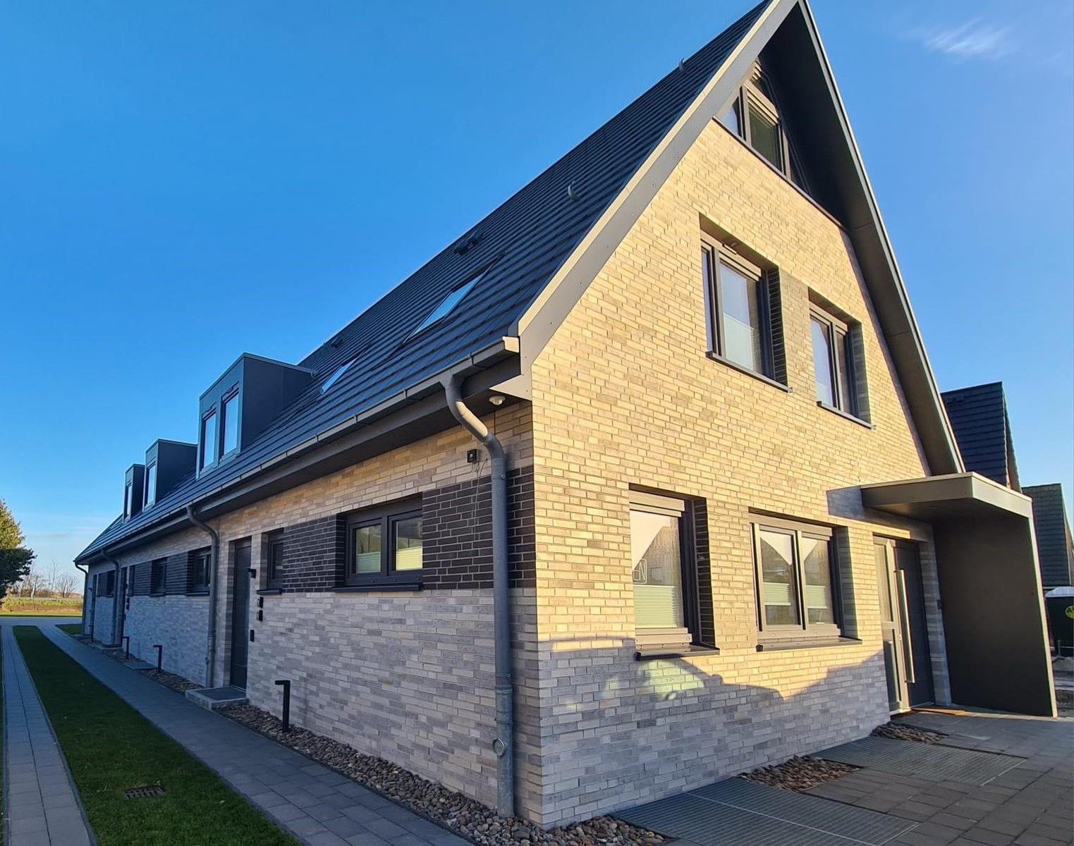 Moderne zweistöckige Villa mit Ziegelfassade und Dachfenstern.