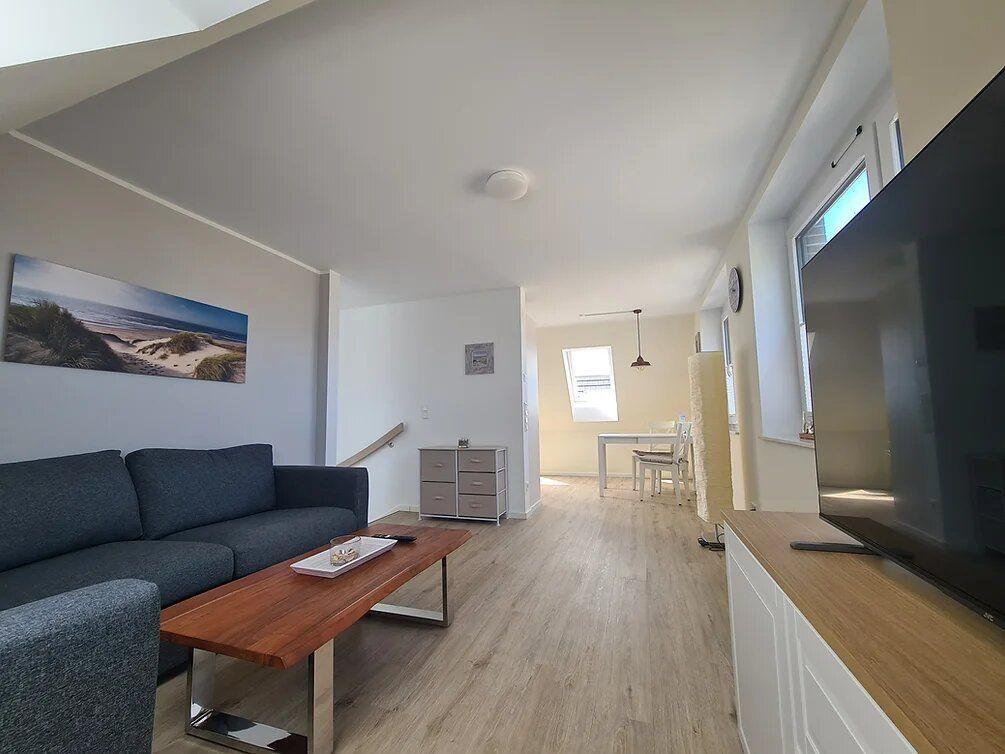 Living room with sofa, coffee table, and TV. Passage to dining area with table and chairs.