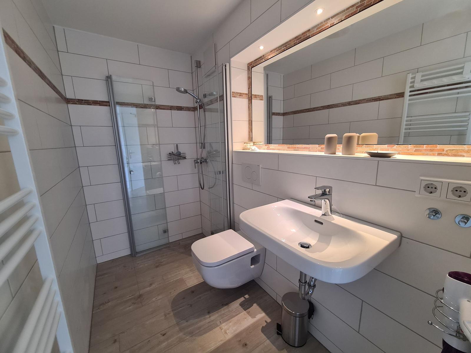Badezimmer mit Dusche, Waschbecken und Toilette.