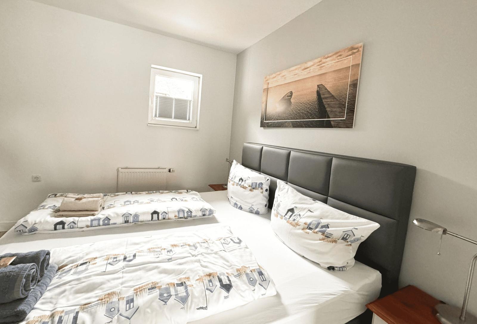 Schlafzimmer mit Doppelbett, Wandbild und Nachttisch.
