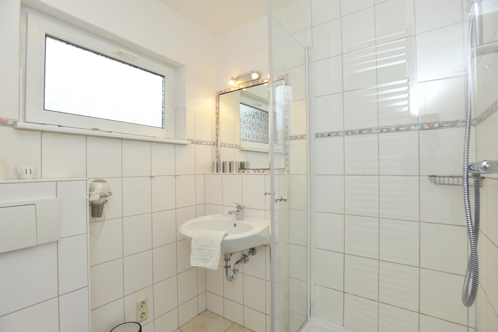 Badezimmer mit Dusche, Waschbecken und Fenster