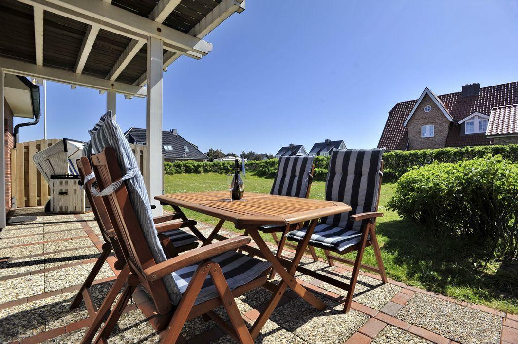 Terrasse mit Tisch und Stühlen, Blick auf Garten und Häuser.