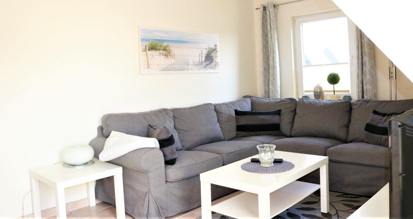 Ein Wohnzimmer mit grauem Sofa, weißem Couchtisch und Wandbild an der Wand.