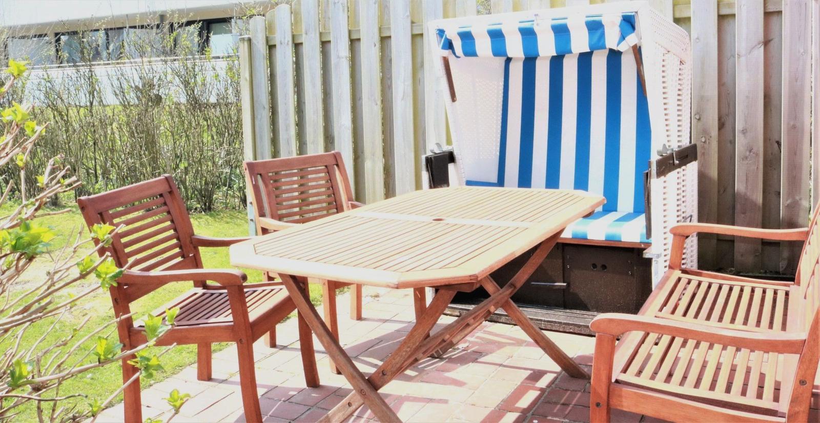 Terrace with wooden table, four chairs, and beach chair with blue-white stripes.