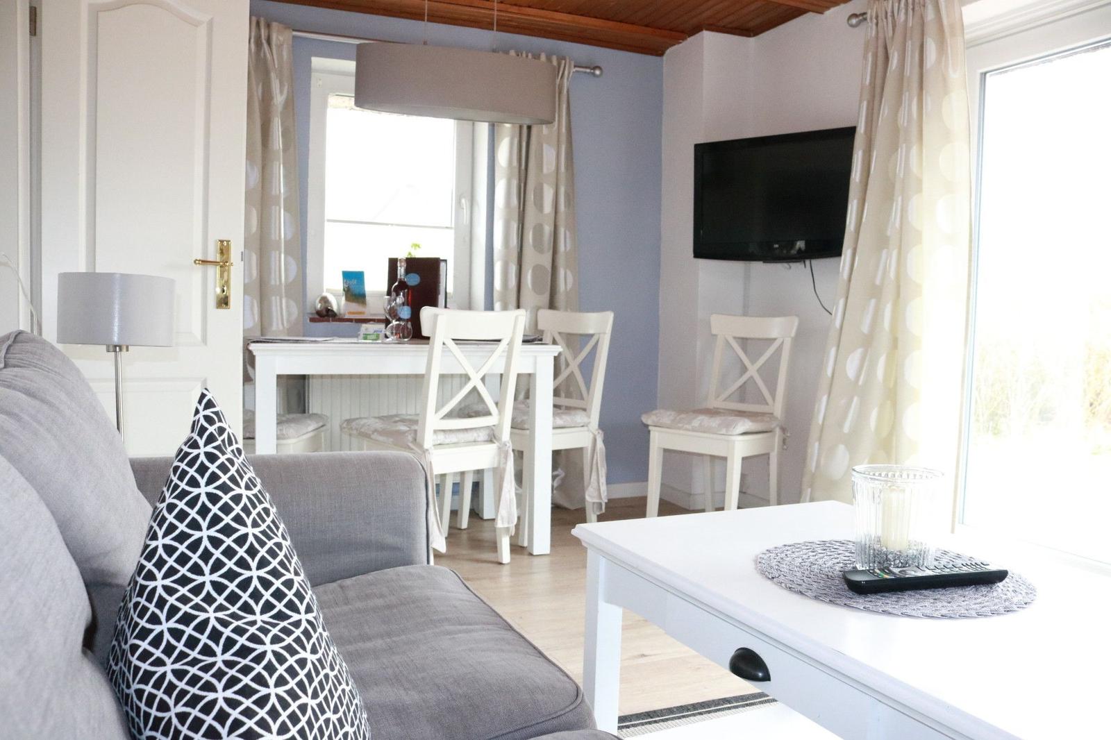 Living and dining area with sofa, table, chairs, and TV.