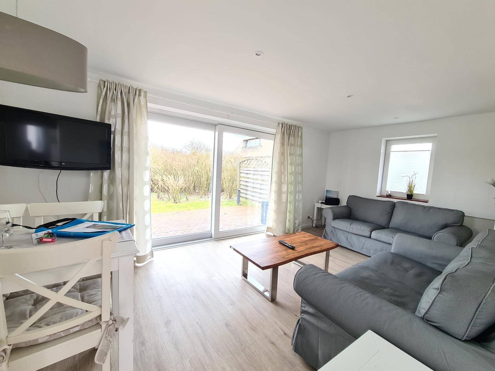 Living room with sofa, TV, and view of the garden.