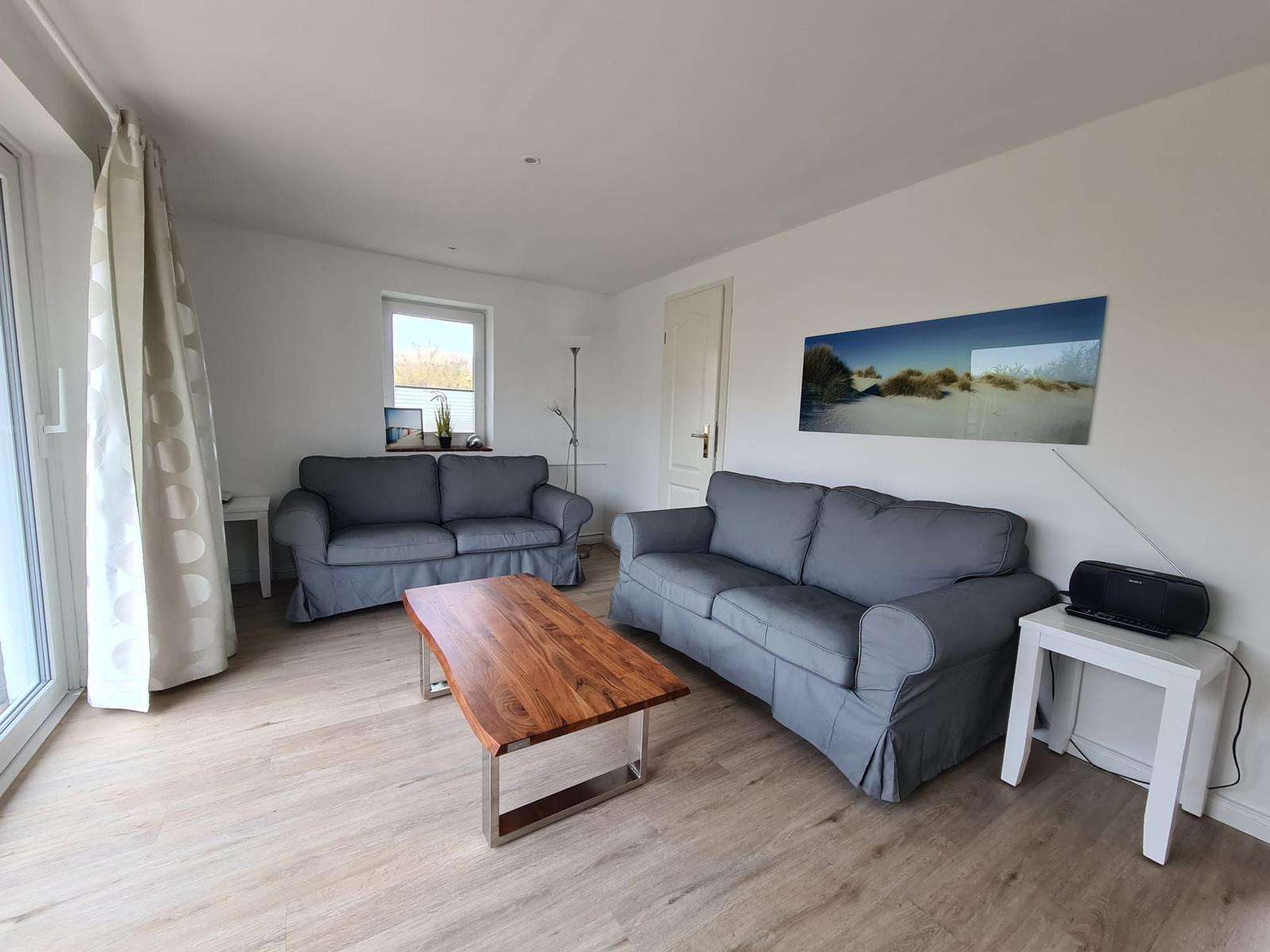 Living room with two sofas, wooden table, and wall art.
