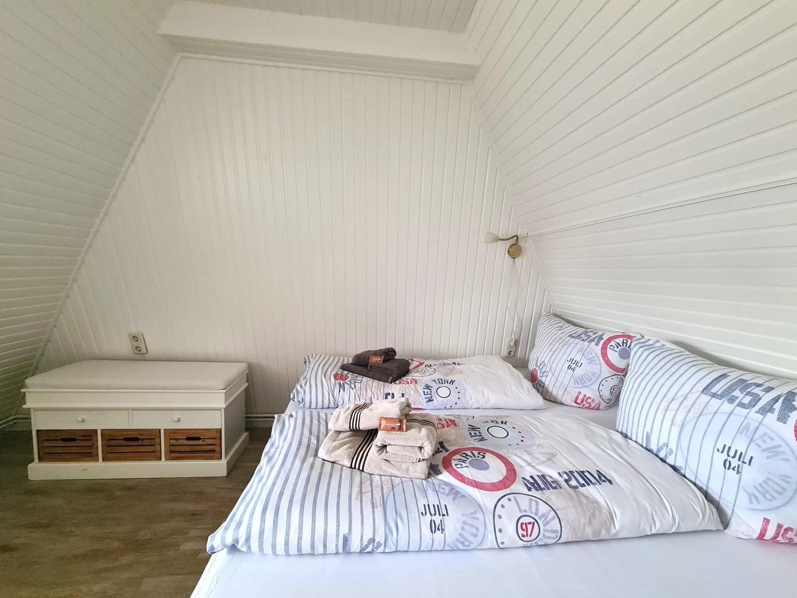 Bedroom with bed, pillows, and nightstand under sloped walls.