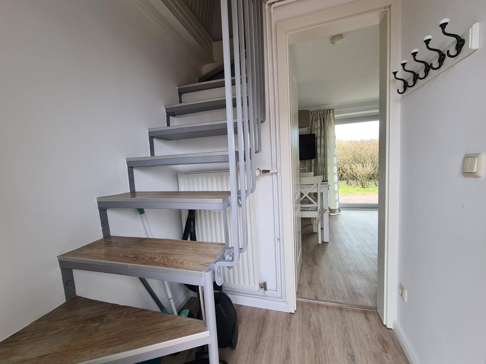 Staircase with wooden steps and view into living area with table and chairs.