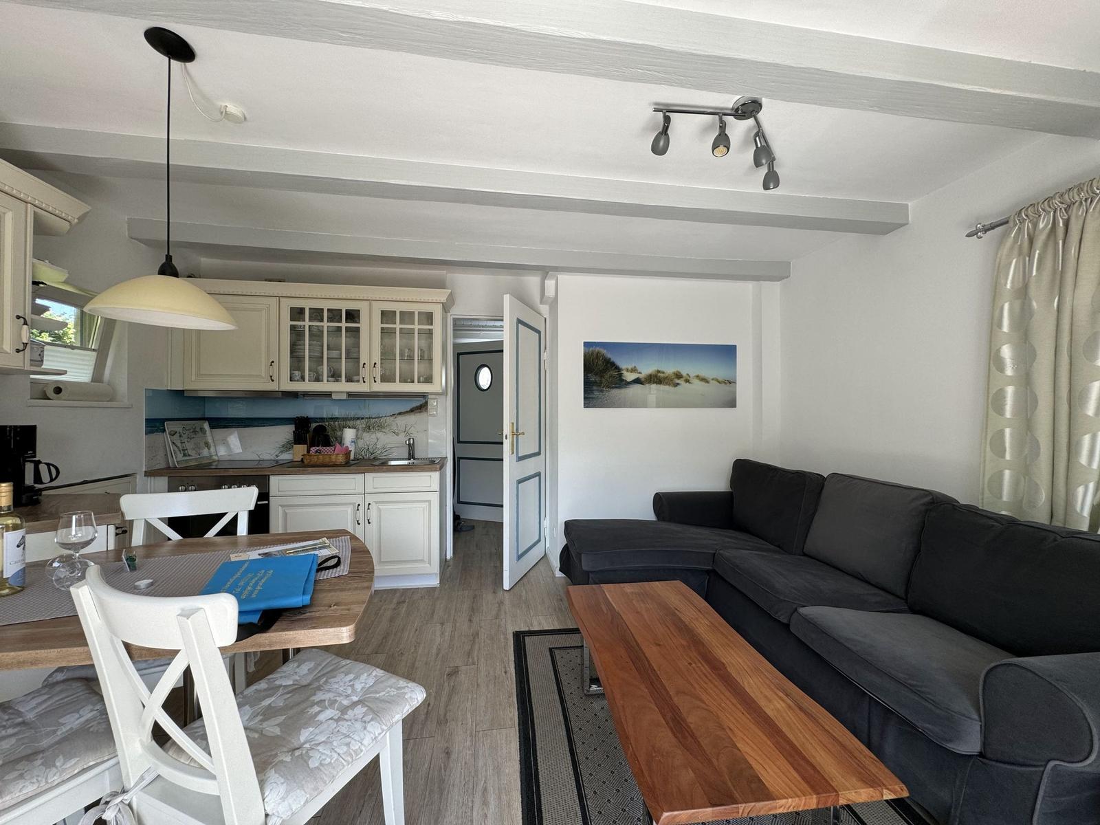 Wohn- und Küchenbereich mit Sofa, Tisch und Küchenzeile.