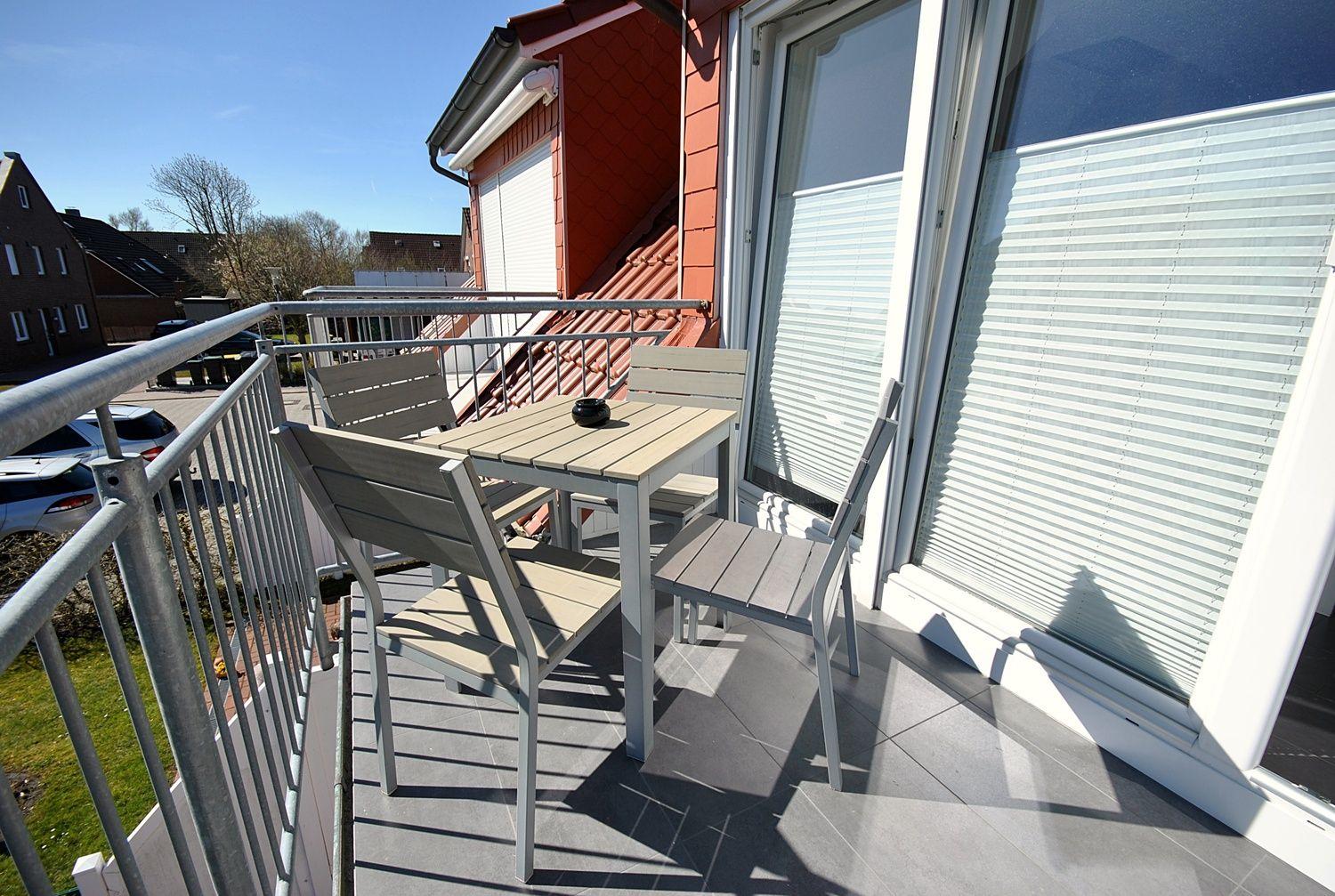 Terrasse mit Tisch und Stühlen, Blick auf Haus und Straße.
