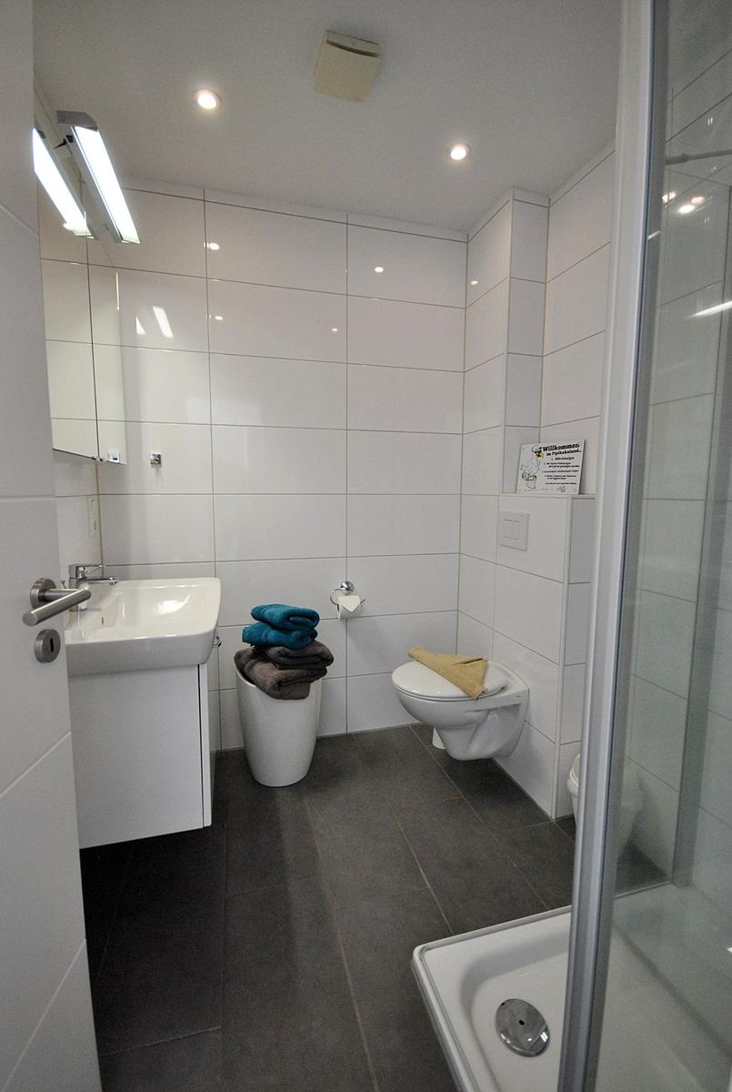 Badezimmer mit Dusche, Toilette, Waschbecken und Handtüchern.