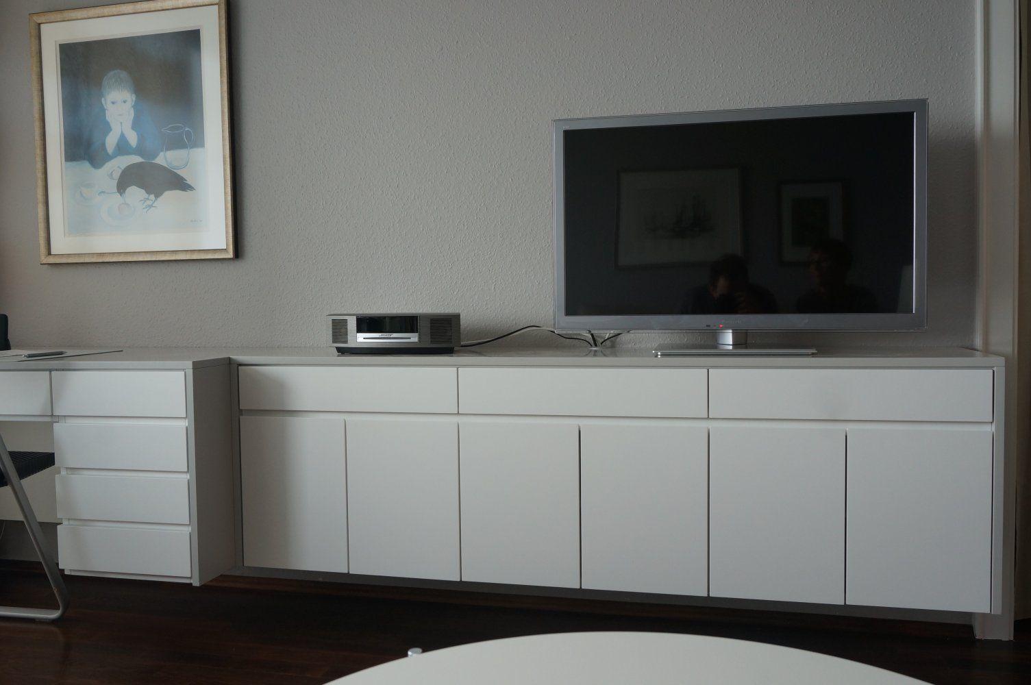 TV auf weißem Sideboard mit Projektor und Bild an der Wand